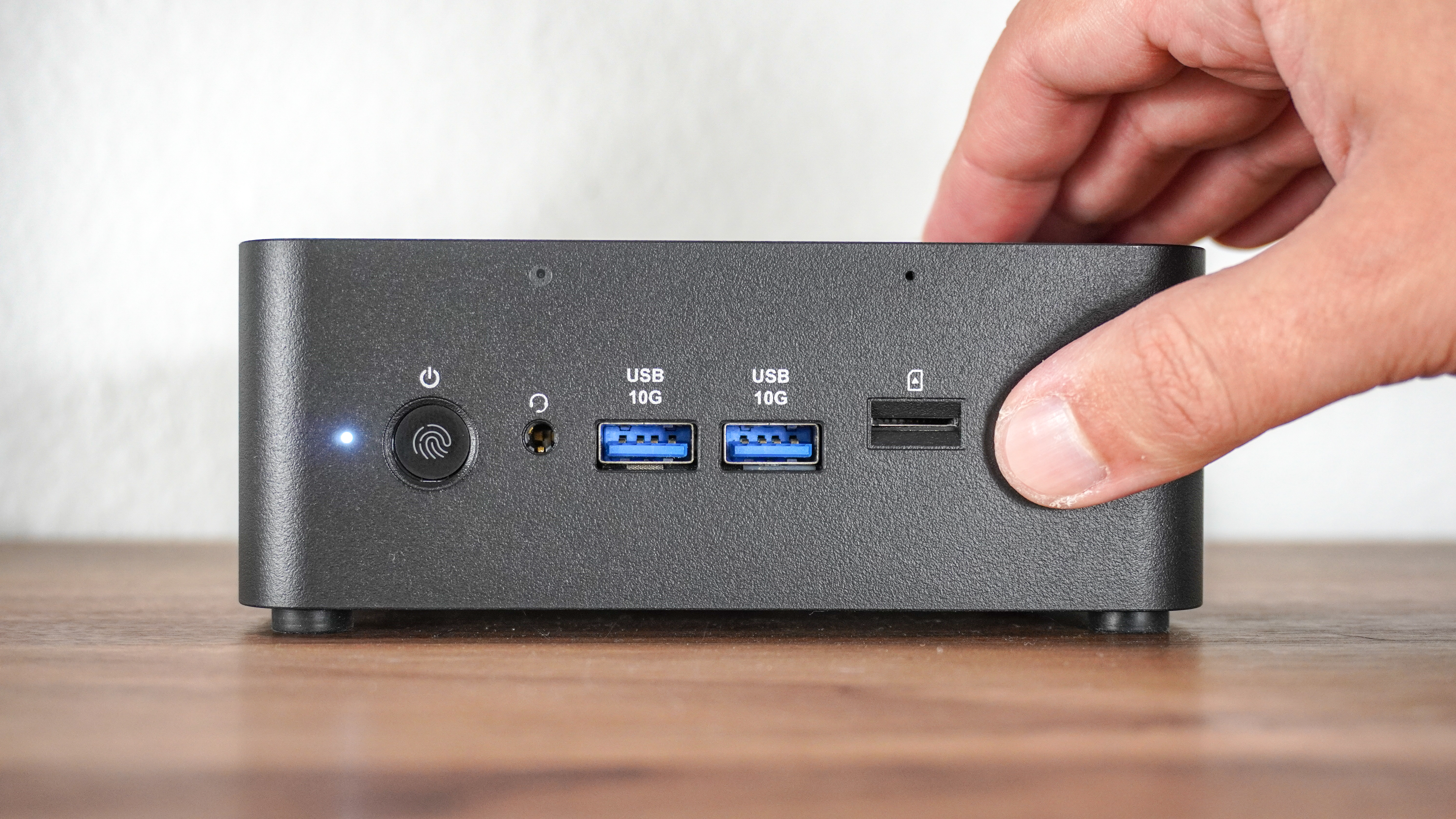 A person pressing the Copilot button on the front of the MSI Cubi NUC AI+ 2MG