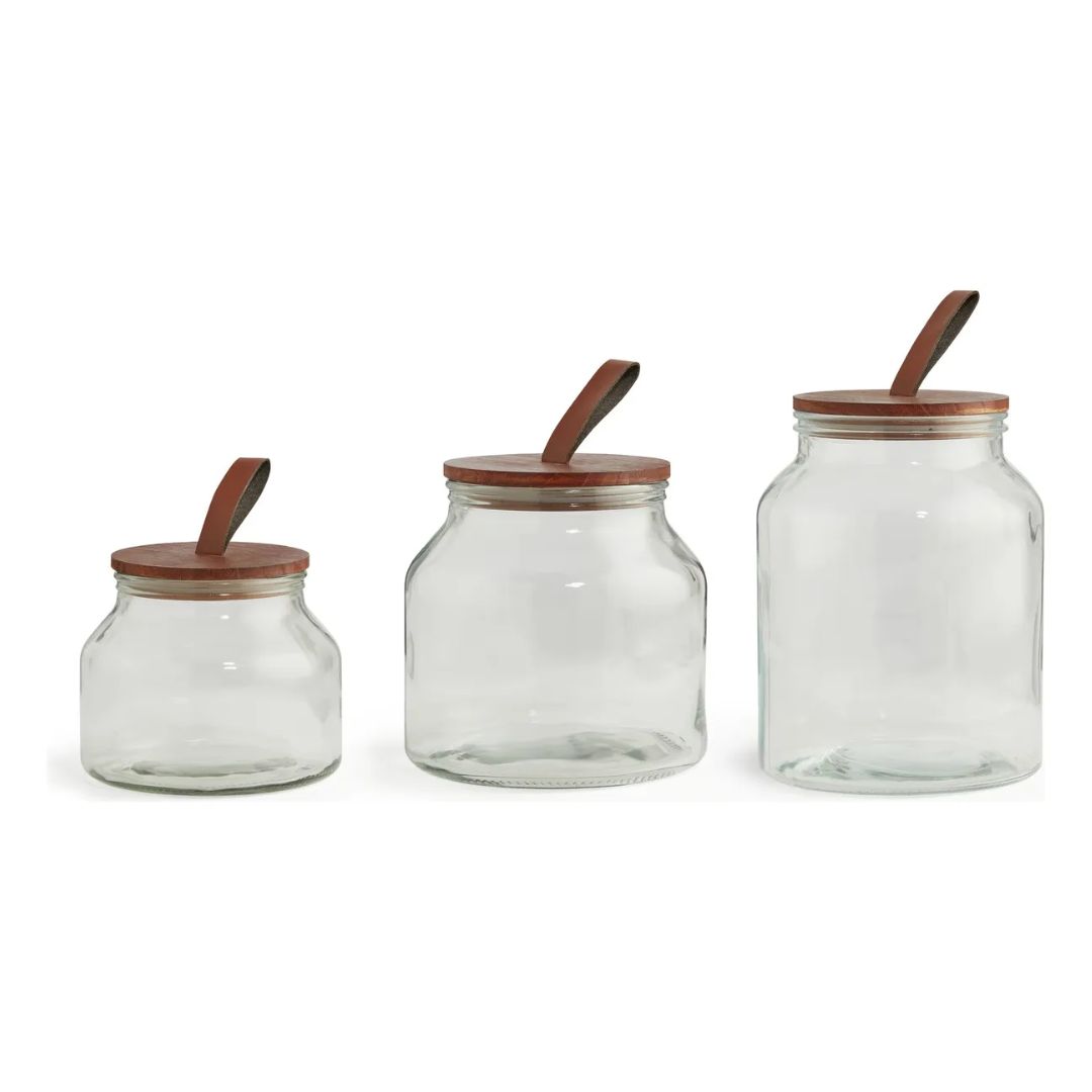 Three glass jars with wooden lids on a white background