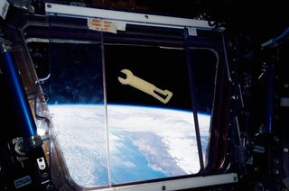 A Kobalt-branded wrench, 3D printed by Made In Space's Additive Manufacturing Facility, floats in front of a window overlooking the Earth aboard the International Space Station.