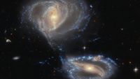 Two galaxies that appear to be in the process of merging. They're both spirals and kind of hazy. They're seen against the backdrop of space.