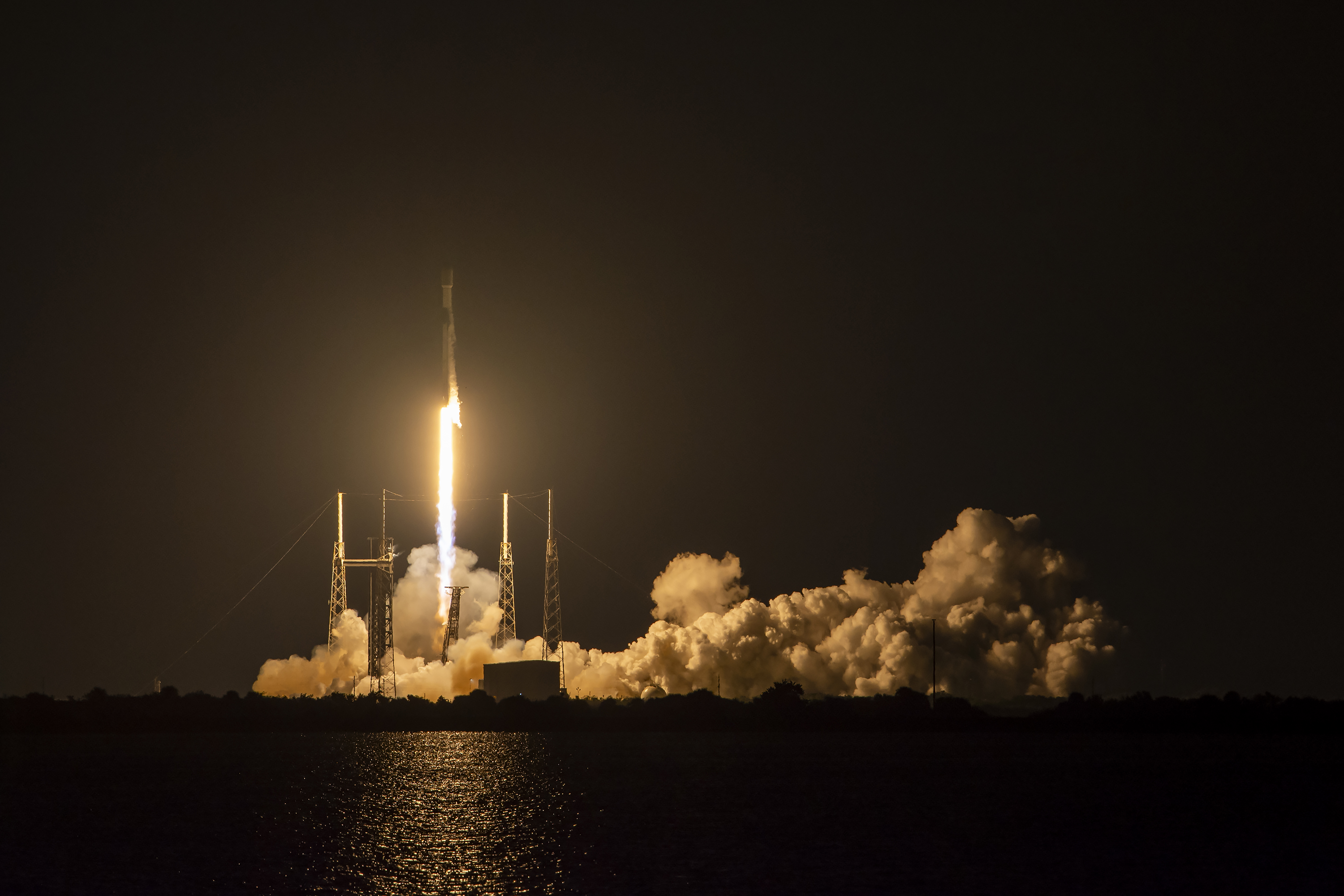 a rocket lifting off into the darkness surrounded by steam