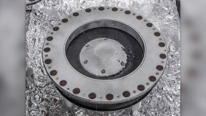 A view of the outside of the OSIRIS-REx sample collector. Sample material from asteroid Bennu can be seen on the middle right. Scientists have found evidence of both carbon and water in initial analysis of this material. The bulk of the sample is located inside.