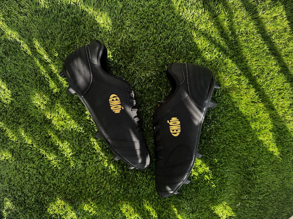 Black Lemon football boots on green grass