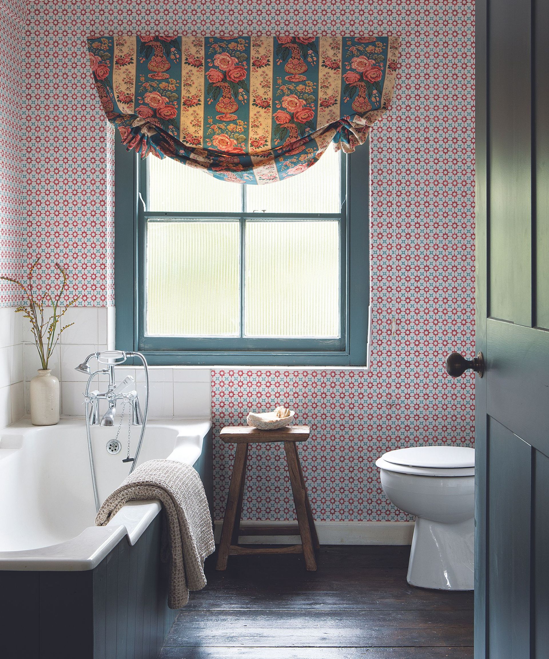 Pink and green wallpaper, blue framed window, black bath base, white tiles