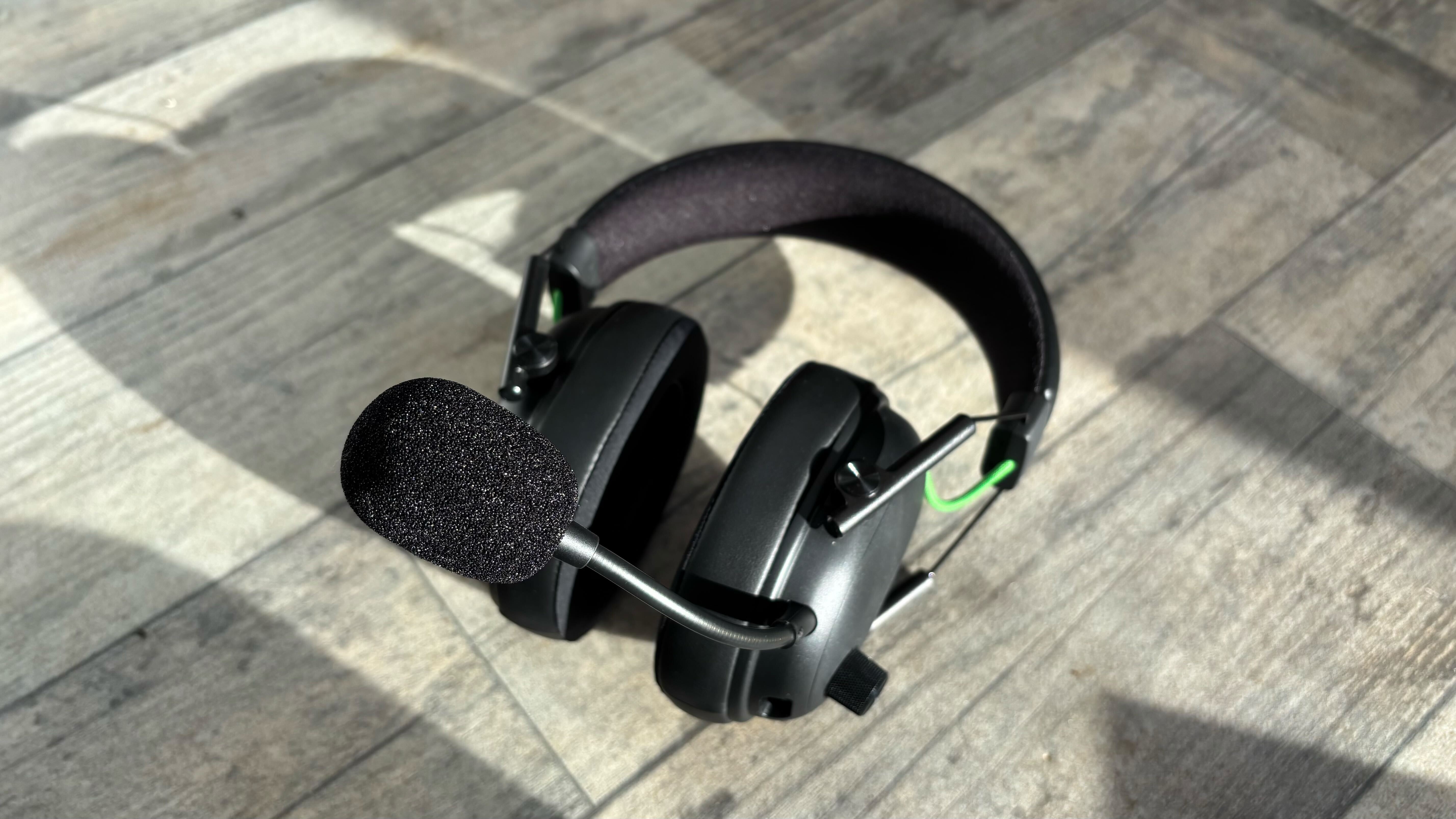 Razer BlackShark V3 wireless headset lying down on a wooden surface with the microphone pointing up