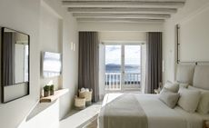 Room with bed, television and mirror, small balcony overlooking the ocean