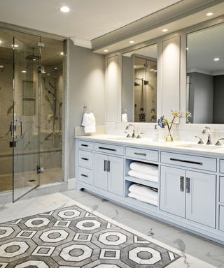 A bathroom with grey and white octagonal patterned marble floor and powder blue vanity