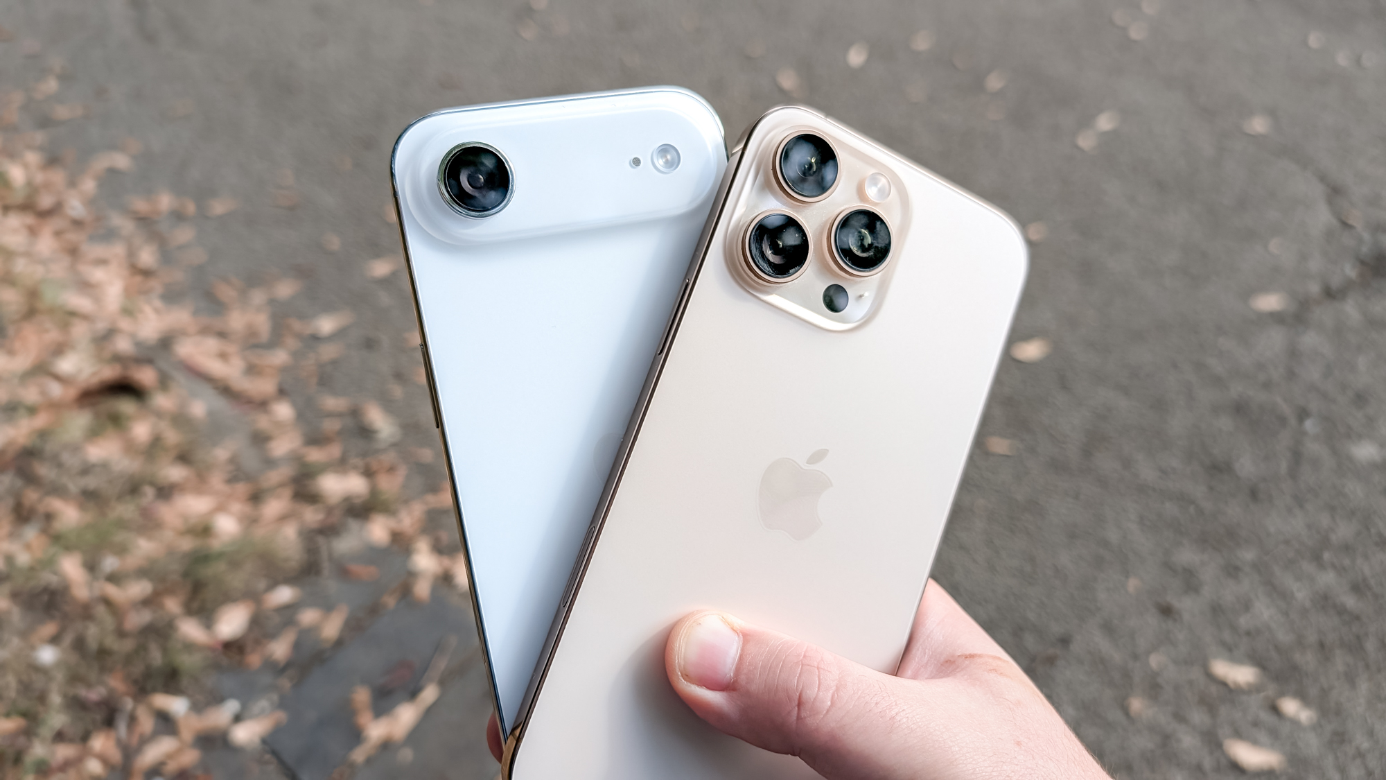 The iPhone Air and iPhone 16 Pro Max held together over an asphalt path