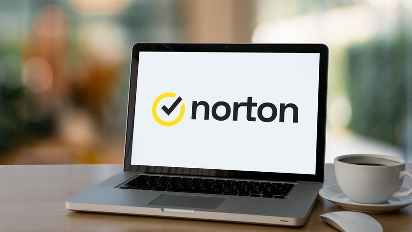 The Norton logo on a laptop next to a cup of coffee.