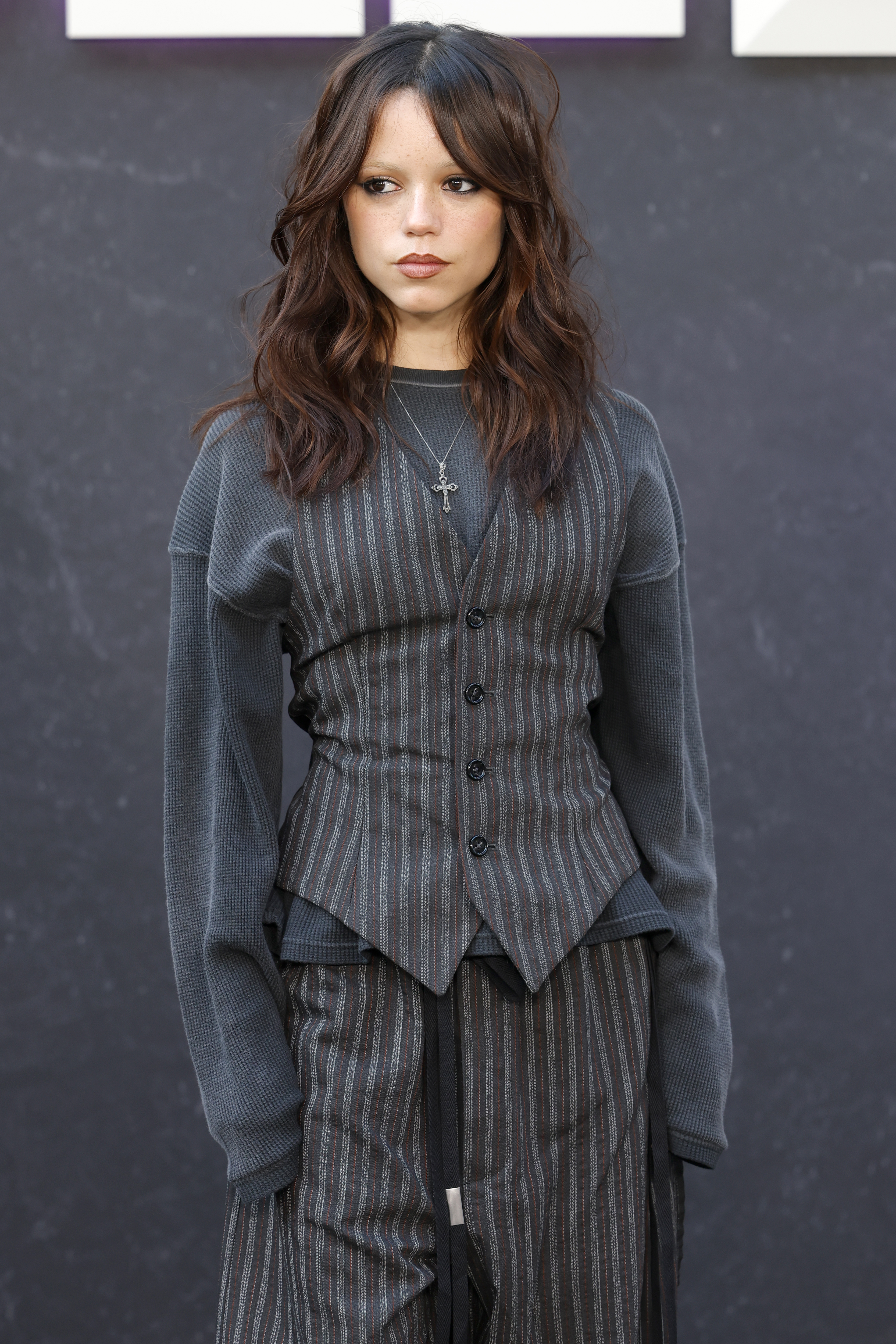 Jenna Ortega attended a Wednesday event in a pinstripe suit set layered over an oversize long-sleeve
