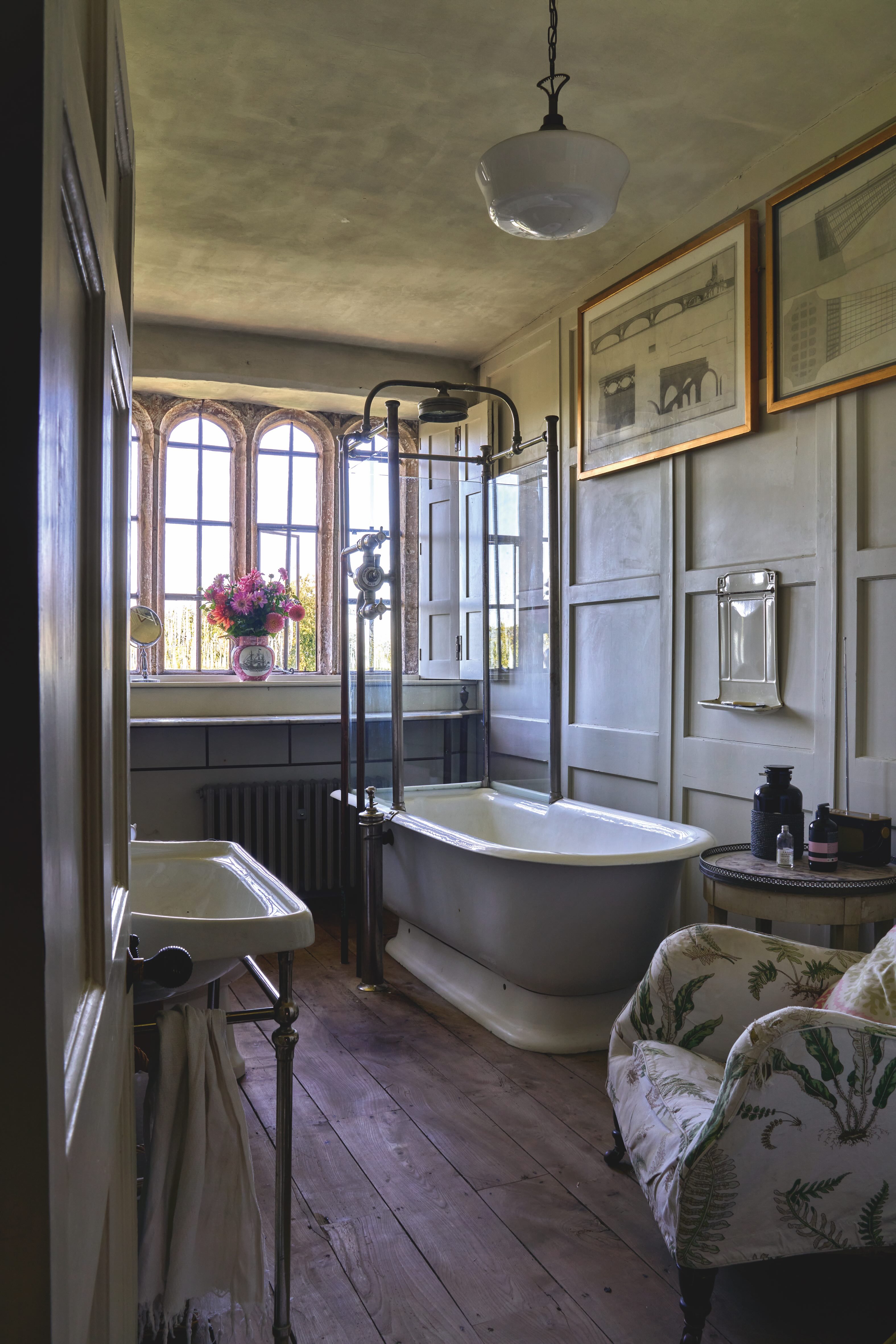 A bathroom with a vintage bathtub and shower. There is also a chair