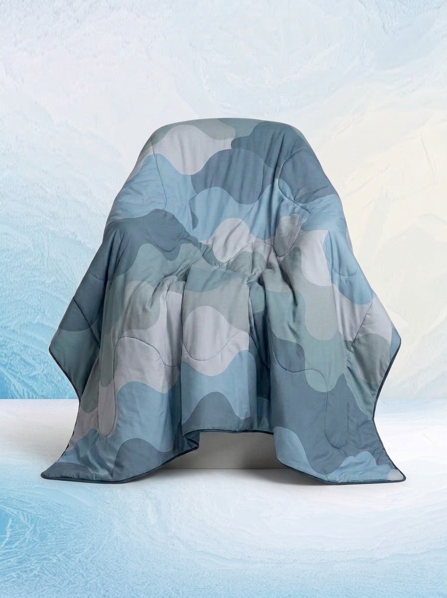 A Wave Print Oodie Cooling Blanket against a blue icy background edited by Gemini