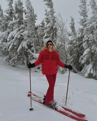 Bettina Looney wears a white ski jacket, leggings and white snow boots.