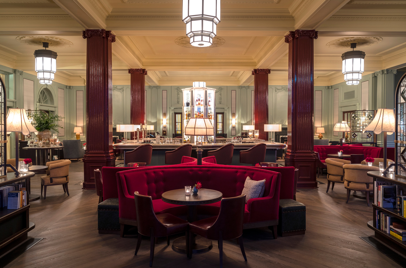 The interior of the Century Bar at Gleneagles Hotel with an island bar surrounded by red banquettes