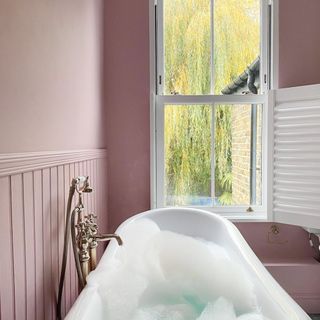 pink bathroom with bath and shutters