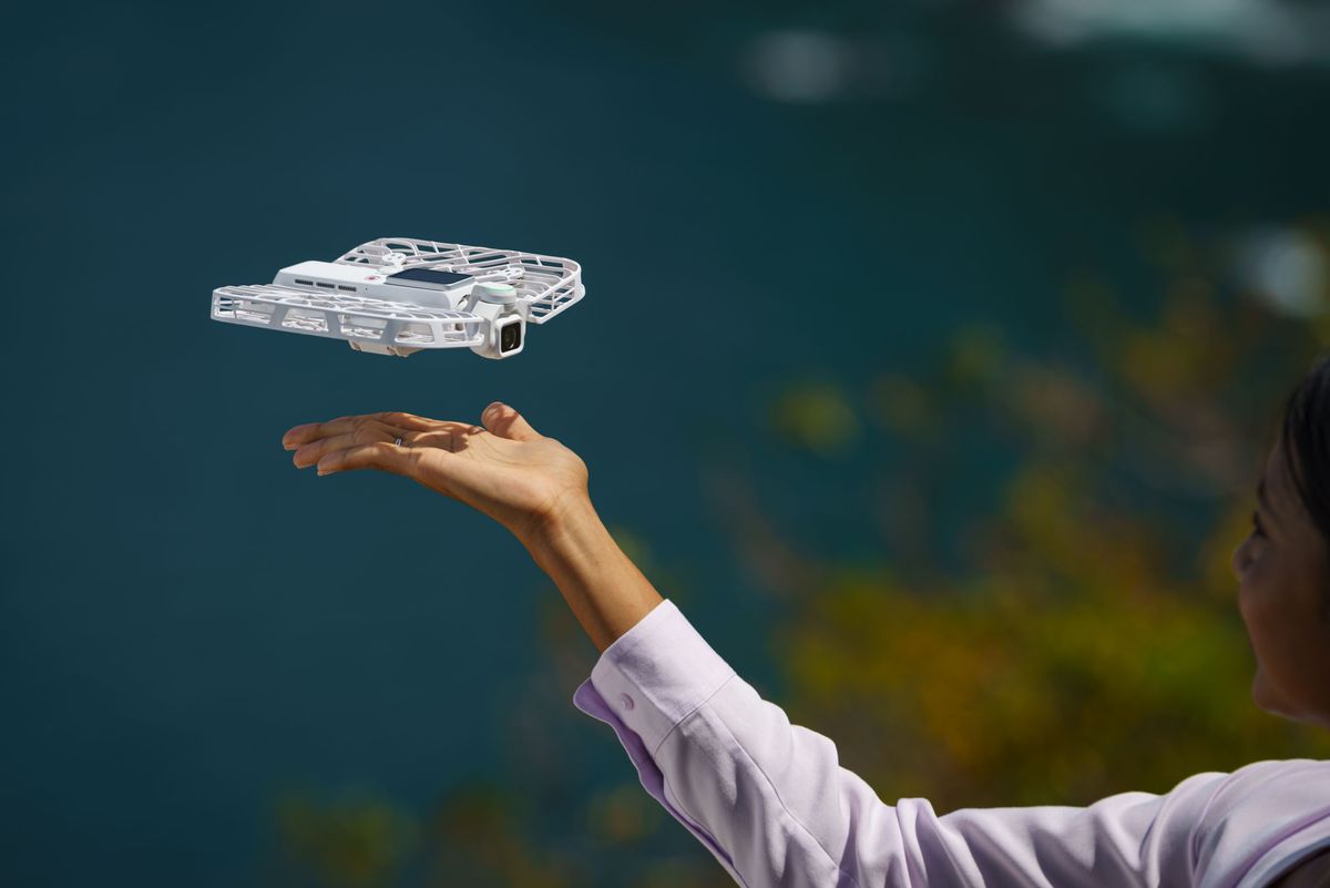 HoverAir Versa 2-in-1 drone and pocket gimbal camera in white, taking off from a person's hand