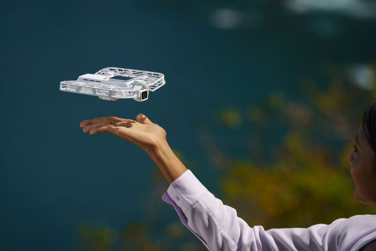 HoverAir Versa 2-in-1 drone and pocket gimbal camera in white, taking off from a person's hand