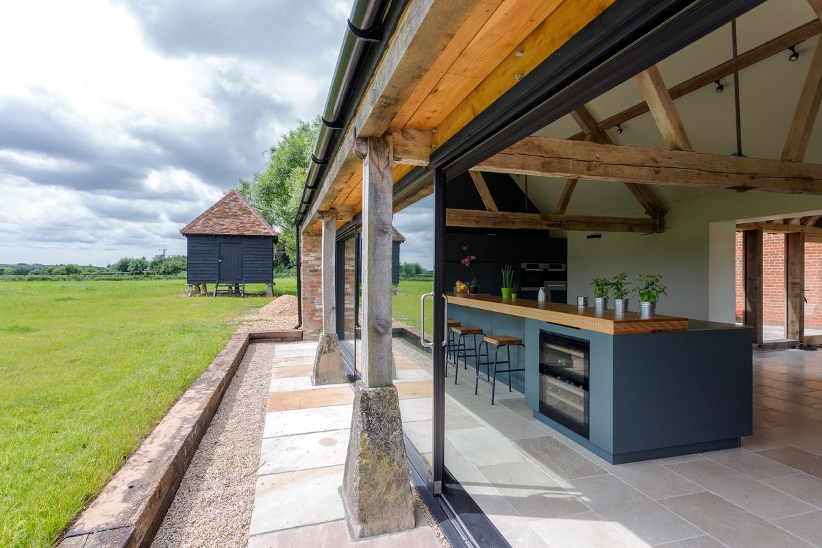 A glass sided modern barn conversion with open fields beyond