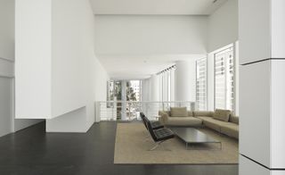 Interior view of modern living room with large rug, corner sofa and two black chairs around coffee table