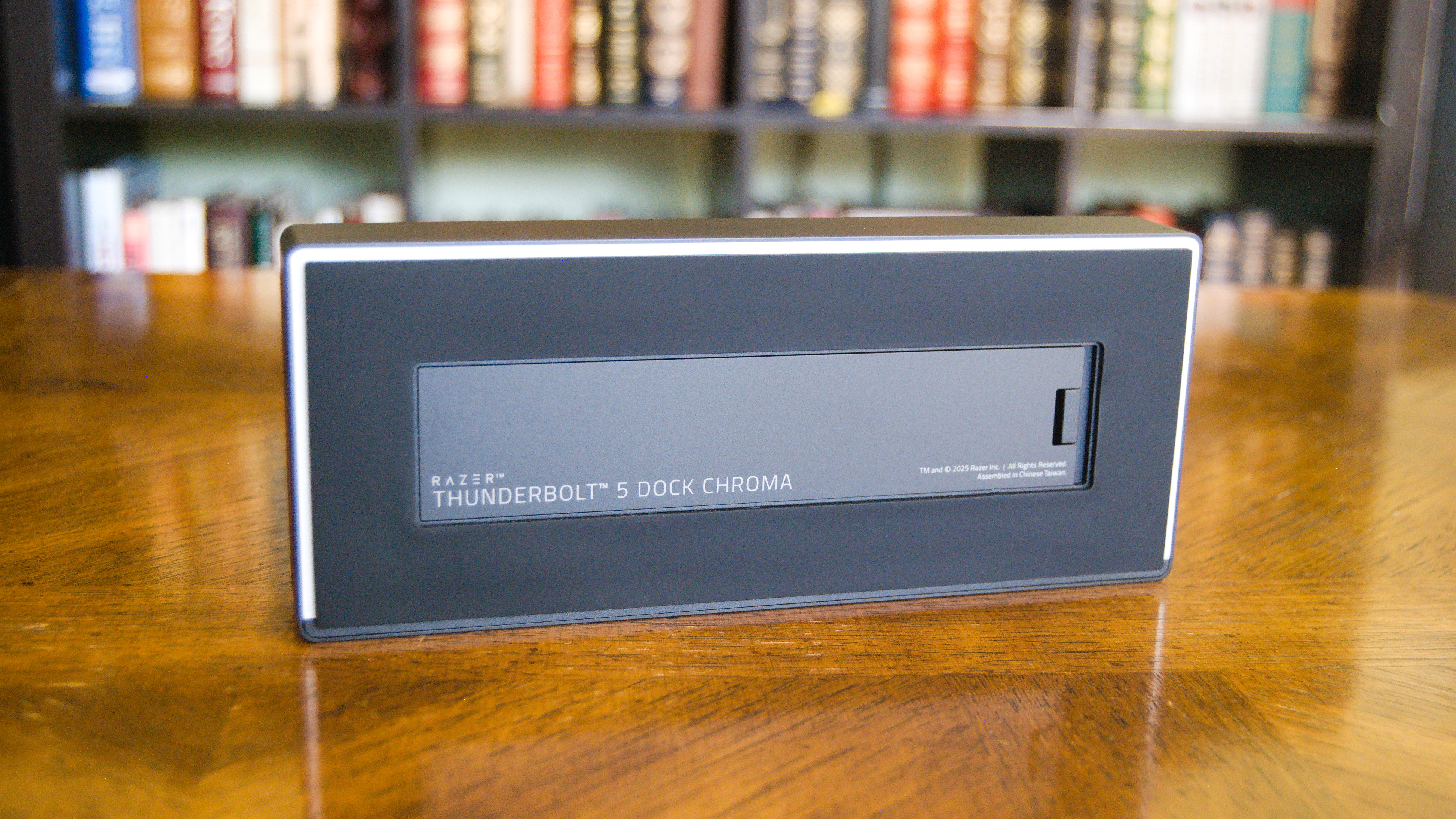 The Razer Thunderbolt 5 Dock Chroma sitting on a table with the bottom SSD enclosure hatch in view.