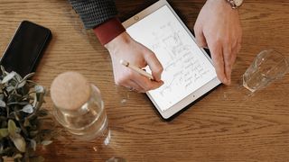 A man not losing his Apple Pencil, using it with an iPad in a cafe 