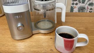 Zwilling Enfinigy Drip Coffee Maker next to a half-full cup of coffee