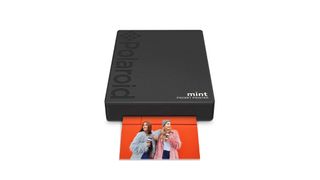 The Polaroid Mint Pocket Printer, producing an image of two long-haired people against a red background