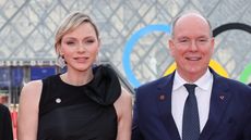 Princess Charlene, wearing a black jumpsuit, and Prince Albert, wearing a suit, pose for a photo outside the Louvre before a gala dinner