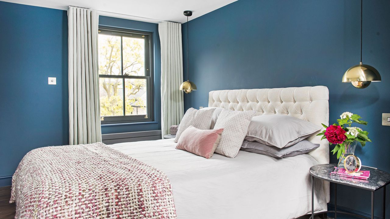 Blue bedroom with grey curtains and white bed