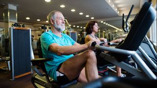 Two people on recumbent exercise bikes in gym