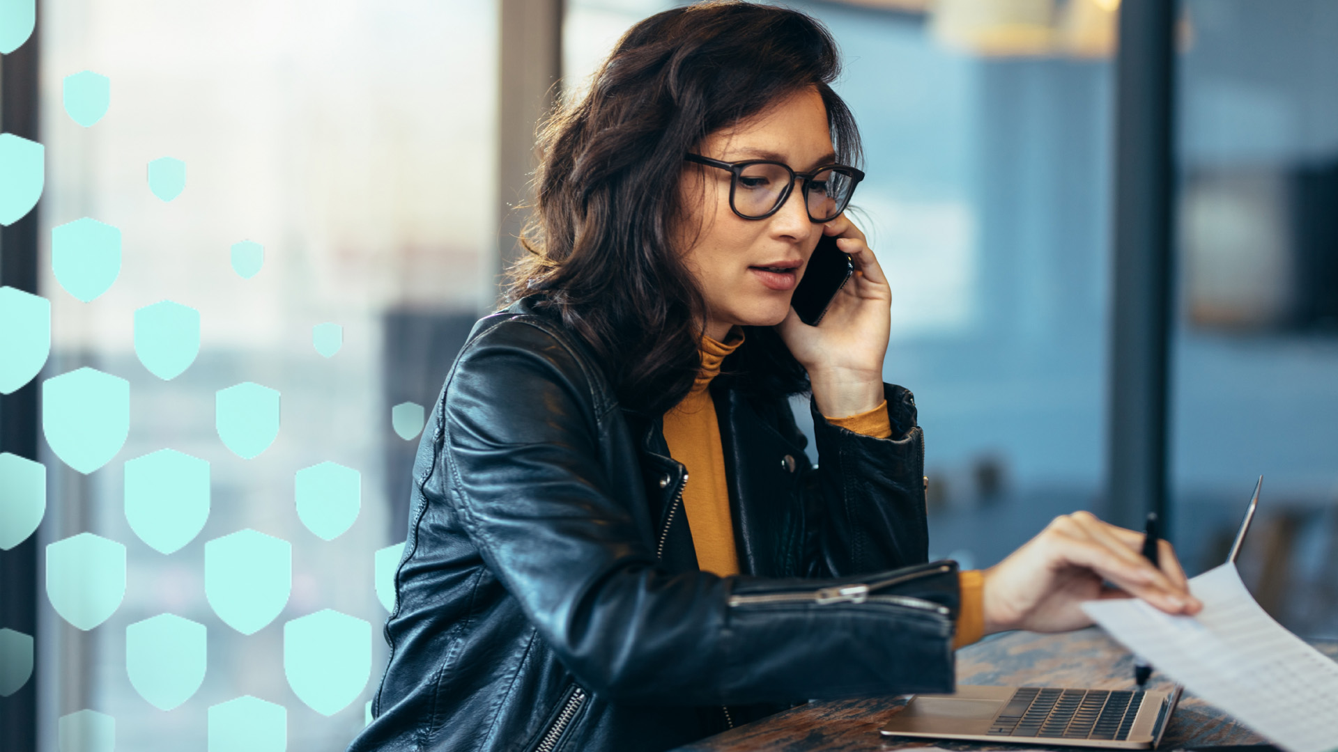 A woman in a black jacket on the phone and shuffling papers