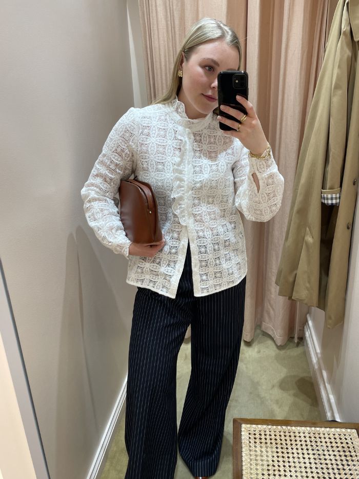 Woman wears embroidered blouse, pinstripe trousers