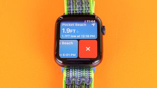 Apple Watch SE 2022 on an orange table with the new Tides app screen displayed