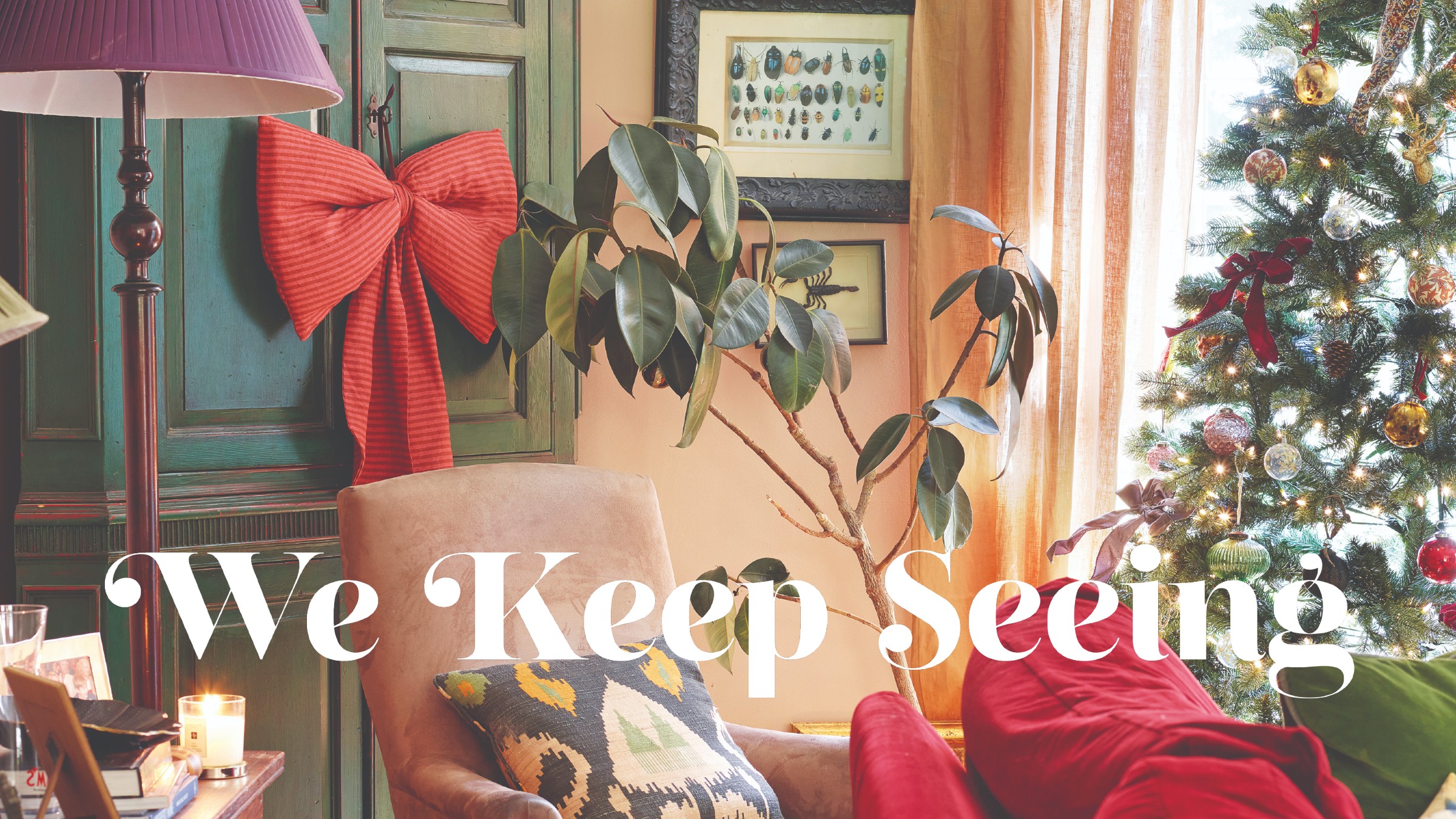 A living room decorated for Christmas with a bow-adorned Christmas tree and a cabinet decorated with a large striped bow