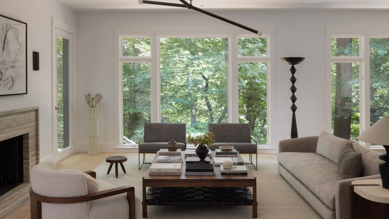 living room with beige sofa and cream walls and with large windows and views of trees 