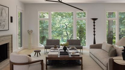 living room with beige sofa and cream walls and with large windows and views of trees 