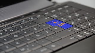 Un clavier d'ordinateur portable avec la touche "Entrée" barbouillée de l'emblème du drapeau européen et RGPD