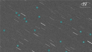 Telescope image of space debris from the Russian Cosmos 1408 satellite shortly after destruction. The image is grainy and grey, with debris circled in blue.