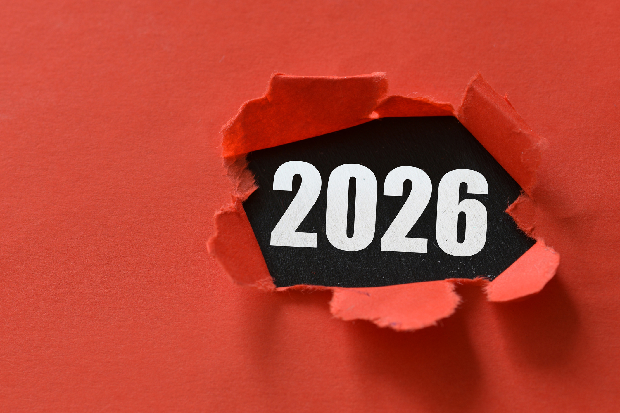 2026 numbers showing through a ripped red paper