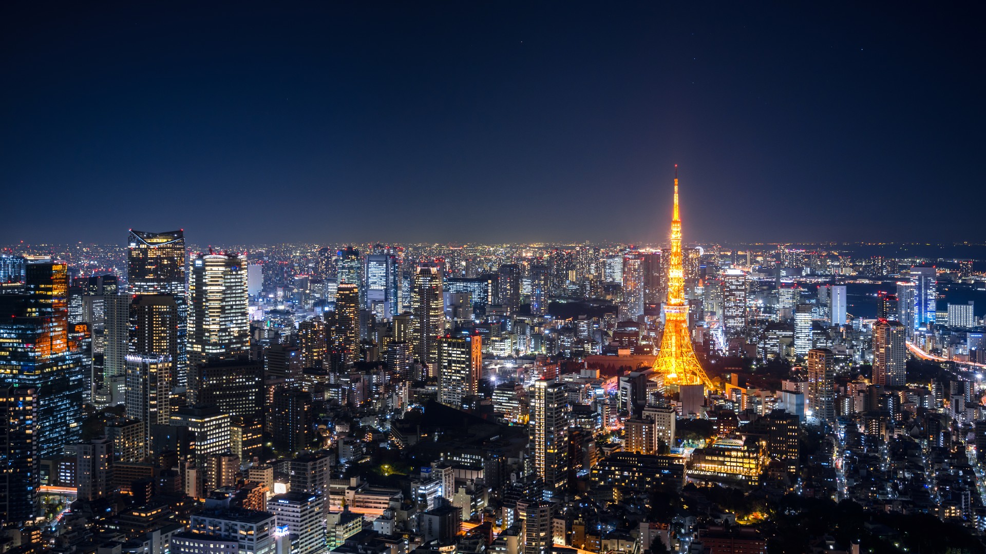 Vista aérea del horizonte de Tokio por la noche, Japón.  Vista elevada de una Torre de Tokio brillantemente iluminada y rascacielos llenos de gente en Tokio por la noche.