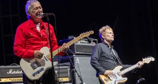 Steve Diggle wears a red shirt and plays a Telecaster onstage with the Buzzcocks
