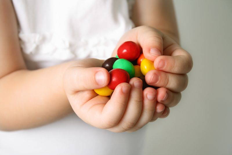 A little girl holds a handful of candy