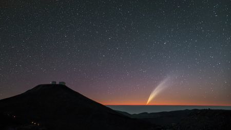 a fuzzy streak of light close to the horizon below a sky full of stars