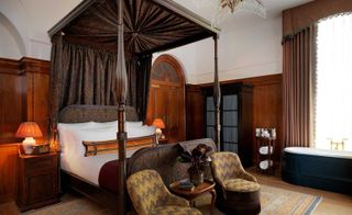 Bedroom featuring four-poster bed and walls lined in mahogany