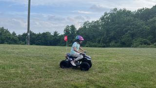 Girl rides Droyd ATV through grass field