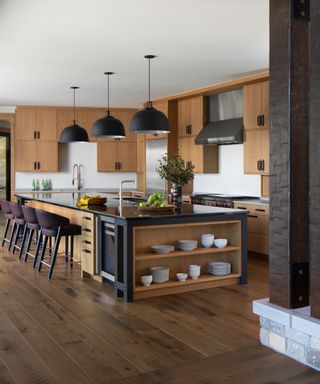 kitchen with oak cabinets, island, black pendants and leather barstools