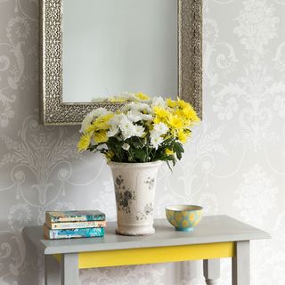 grey designed wall frame on wall and flower pot on grey table