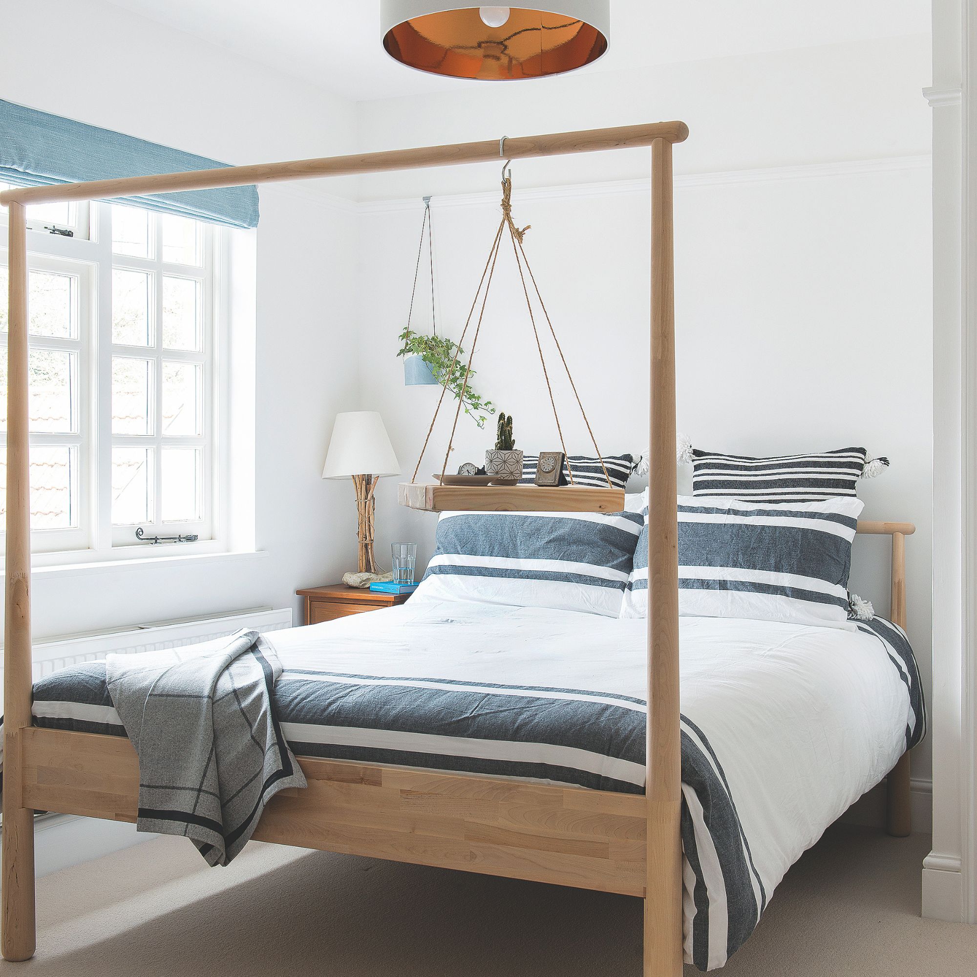 Double bed with wooden frame in light guest bedroom