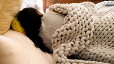 A woman sleeping on her side away from the camera under a knitted weighted blanket