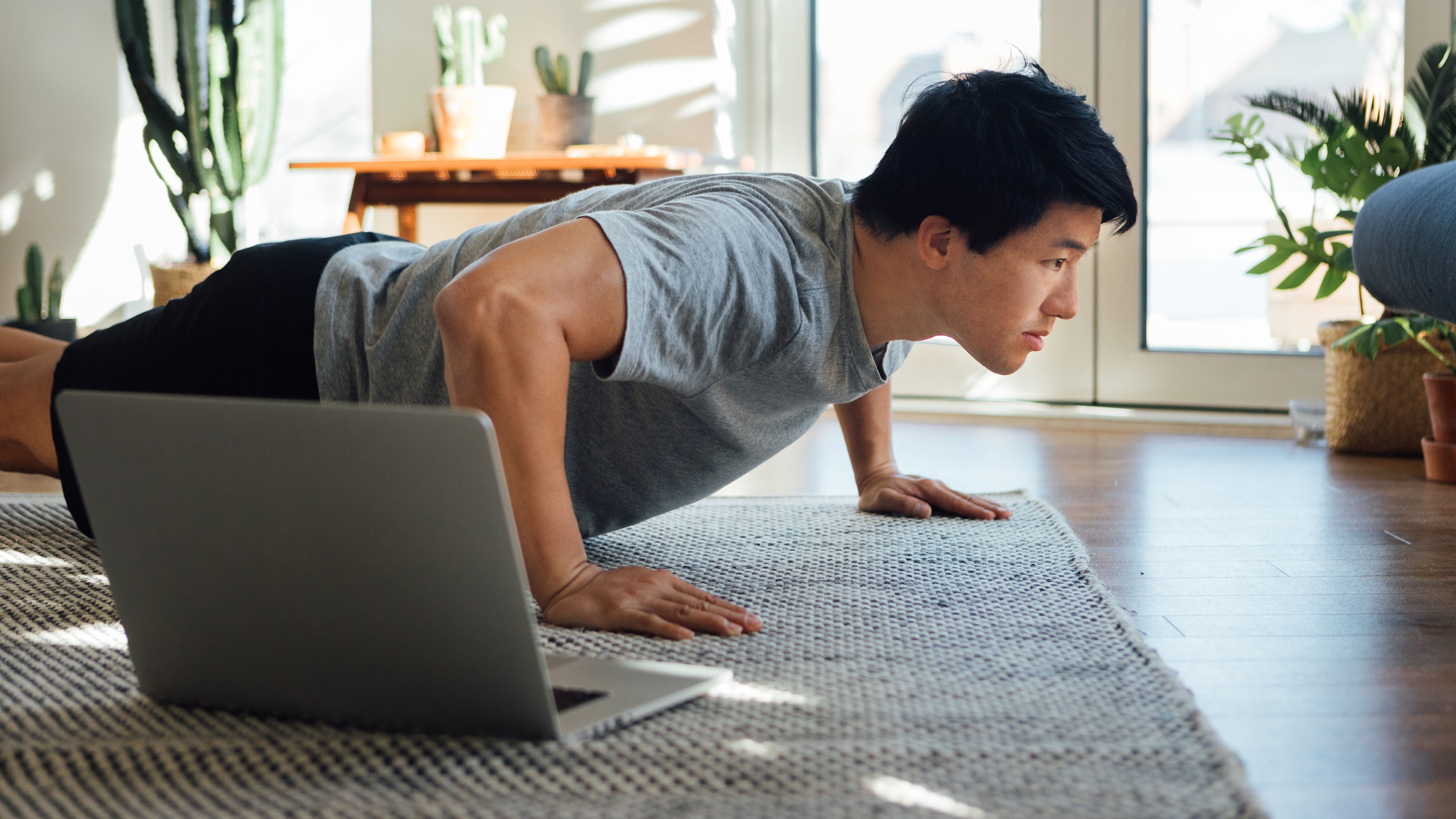 Man doing push-ups next to laptop